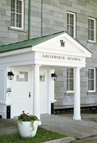 General view of Building 28 (Governor General's Residence), showing its lightwell along the front of the building allowing light into the basement, and the white painted projecting wood porches that span the lightwell, 1993.; Parks Canada Agency/Agence Parcs Canada, C. Rodriguez, 1993.