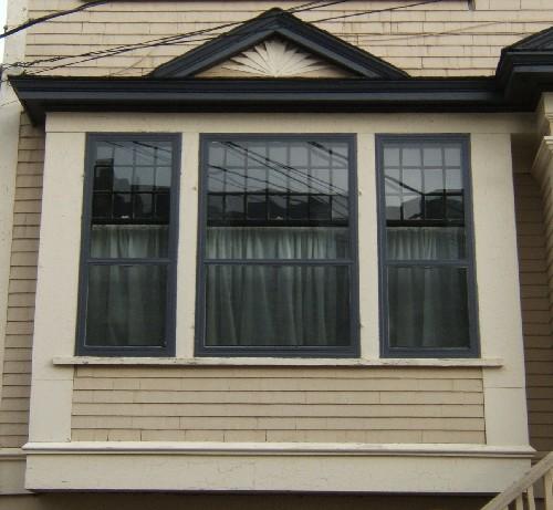 This image provides a view of one of the single storey bay windows crowned by a pediment and encasing tripartite window, 2005; City of Saint John