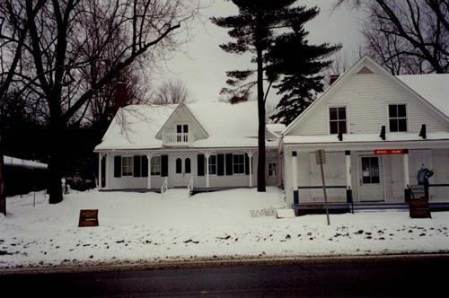 View of the St. Laurent Store and Warehouse on right, showing the inviting covered gallery and the balanced proportions, 1993.; Parks Canada Agency / Agence Parcs Canada, 1993.