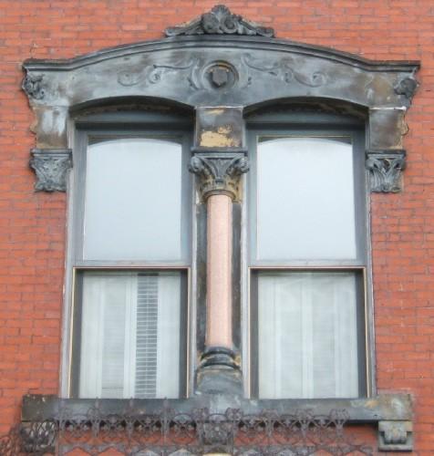 This image provides a view of one of the segmented arched windows separated by a Corinthian column, along with sandstone elaborate entablature and sill, 2005; City of Saint John