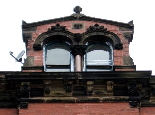 This image provides a view of the gable dormer crowned with a finial, encasing Roman arched windows above the bracketed cornice, 2005; City of Saint John