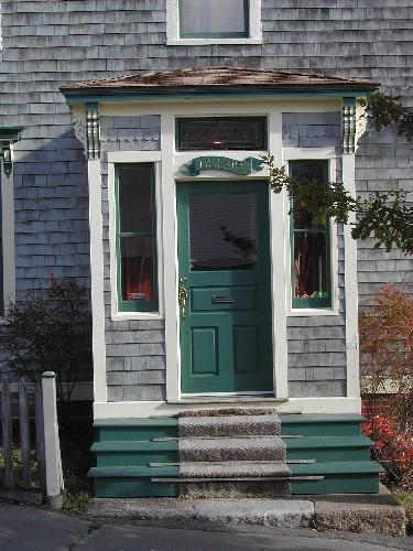 This photograph shows the porched entrance to the home, and illustrates the leaded glass transom window and brackets, 2005; City of Saint John