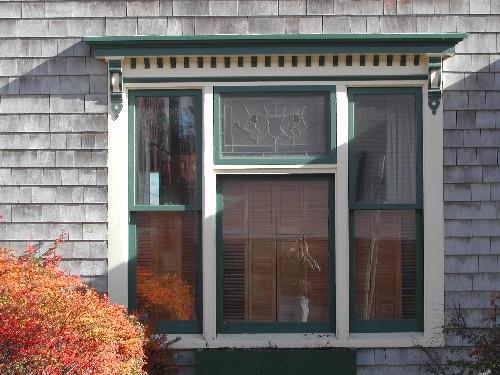 This photograph shows the triple window with a bracketed entablature ornamented by dentils. It also illustrates the leaded glass pane in the central upper panel of the central window, 2005; City of Saint John