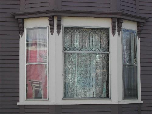 This photograph shows the triple set openings in the bay window, and illustrates Arts and Crafts detailing in the upper pane of the central window, 2005; City of Saint John