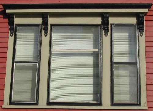This image provides a view of the triple windows with entablature supported by four, decorative scroll brackets, 2005; City of Saint John