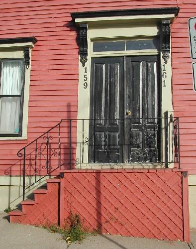 This image provides a view of the central entry consisting of a wood entablature, two broad, decorative brackets, a rectangular, two-paned transom window and double wooden doors with glass panels, 2005
; City of Saint John