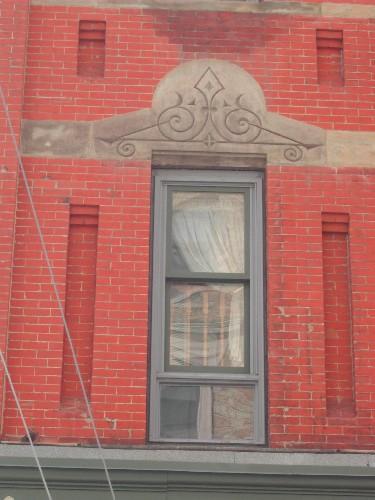 This photograph shows a window with an ornate sandstone lintel, 2005; City of Saint John