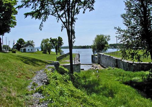 General view of Carillon Canal, showing the relationship between the superintendent’s residence, the old house of the toll collector, the entry to the first canal and lock number one of the second canal, 2003.; Parks Canada Agency / Agence Parcs Canada.