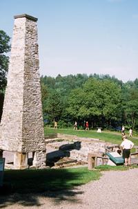View of the chimney and remains of the lower forge at Forges du Saint-Maurice National Historic Site of Canada, 2002.; Parks Canada Agency / Agence Parcs Canada, E. Kedl, 2002.