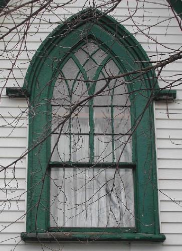 This image provides a view of the Gothic arch window in the central gable with decorative wood tracery and label hood moulding with stops, 2005; City of Saint John