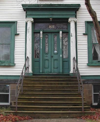 This image provides a view of the prominent central entry consisting of a large entablature supported by wooden Ionic columns, a transom window, side lights and paired wood doors with glass panels, 2005; City of Saint John