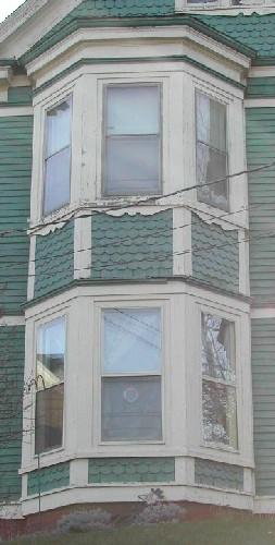 This image provides a view of the two-storey, off-centered bay window with fish-scale shingling in the spandrel panels between storeys, 2006; City of Saint John