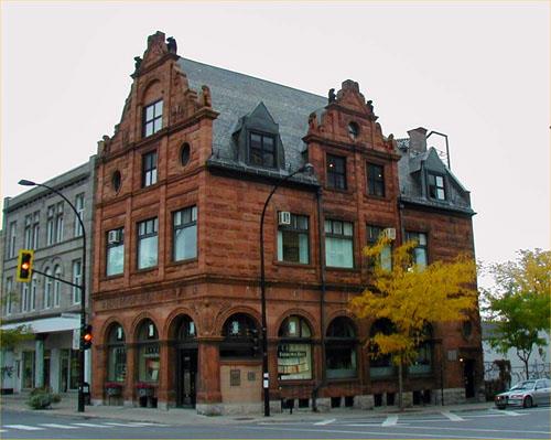 General view of the Bank of Montréal emphasizing its high roof with intersecting sculpted pediments of the gables and dormers, 2004.; Parks Canada Agency / Agence Parcs Canada, 2004.