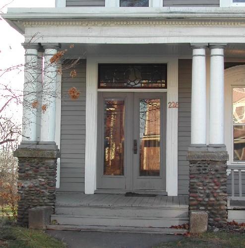 This image provides a view of the entrance including the stained glass transom window over paired wood doors with glass panels, 2006; City of Saint John