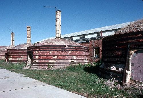 General view of Medalta Potteries, showing the beehive kilns with their brick exteriors, roof monitors, and roofing of wood shingles.; Parks Canada Agency / Agence Parcs Canada.