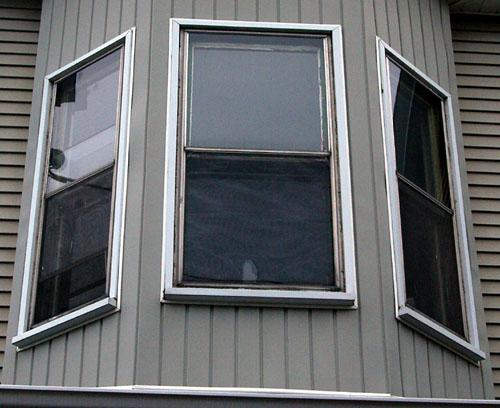 This image shows vertical sliding wood windows in semi-octagonal two-storey bay; City of Saint John