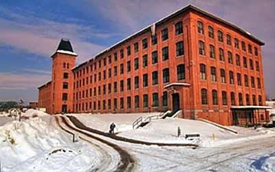 Corner view of the Marysville Cotton Mill showing the regularity of the fenestration, 1995.; Parks Canada Agency / Agence Parcs Canada, J. Butterill, 1995.