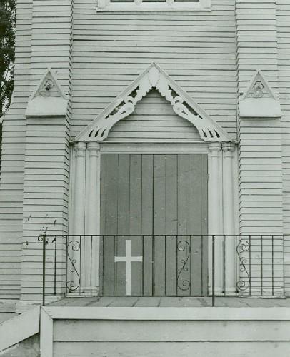 Detail view of Saint Paul's Roman Catholic Church, showing its clapboard cladding and the wooden, twin pilaster surrounds at one of the principal doorways.; Parks Canada Agency / Agence Parcs Canada.