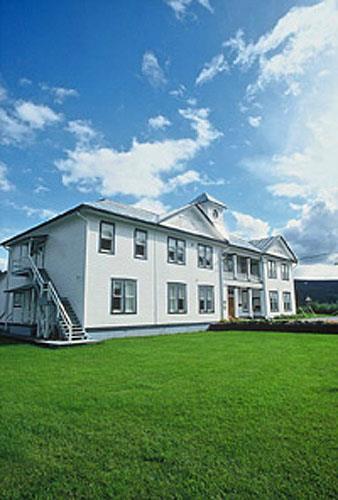 Corner view of the Former Territorial Court House emphasizing the monumental presence and dominant profile of the building with its long, rectangular two-and-a-half-storey massing under a metal hipped roof topped with a lantern, 1995.; Parks Canada Agency / Agence Parcs Canada, W. Lynch, 1995.