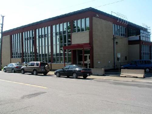 View of the exterior of the Government of Canada Building, showing contrasting colour scheme, which features strong colours for the concrete beams and piers and bright cream-coloured brick infill, 2004.; Department of Public Works and Government Services / Ministère des Travaux publics et services gouvernementaux, Don Macdonald, 2004.