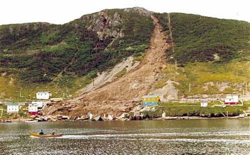 Picture showing the destruction caused by the landslide of August 1973. The remains of houses destroyed by the landslide can be seen at the water's edge.; Government of Newfoundland and Labrador 1973/ HFNL 2009