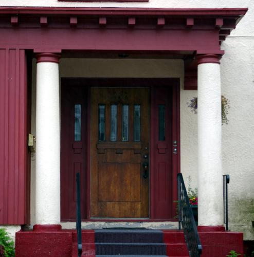 This image shows the portico with doric columns, Craftsman style roof overhang and modillions, Tudor Revival door; City of Saint John
