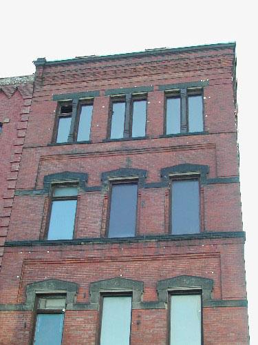 Photograph showing the upper stories and illustrating the windows, recessed brickwork, sandstone ledge, cornice, corbel bands, and sandstone courses; City of Saint John 2004