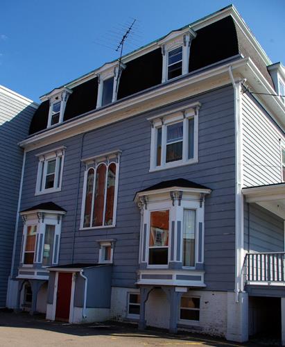 This image shows the symmetrical massing, the brackets, the entablatures, the shiplap siding and the window placement and proportions on the rear façade; City of Saint John