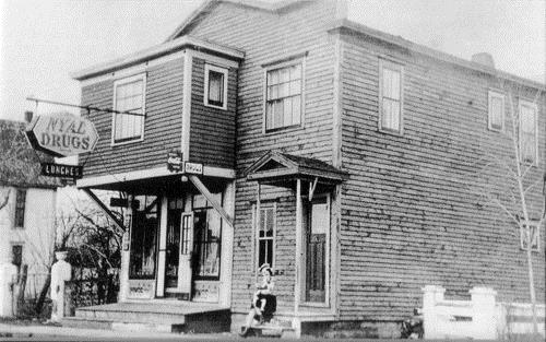 The expanded Camille Bordage Pharmacy, photographed circa 1945.  The sign reads "NYAL Drugs" and a secondary sign says "Lunches".; Private collection