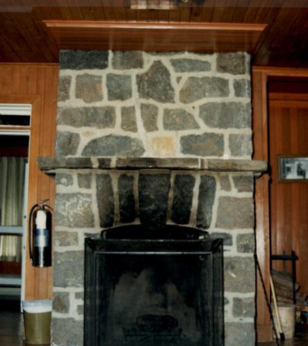 Interior view of Andrew Lodge, showing its stone fireplace with a series of voussoirs surmounting the low-frame arch of the hearth, 1990.; Canadian Parks Services / Service canadien des parcs, 1990.