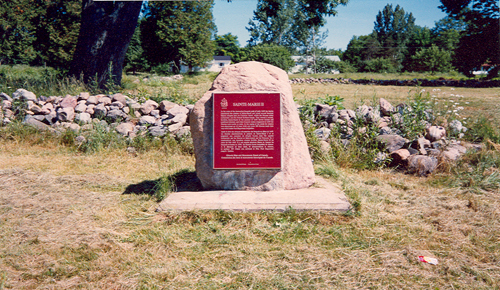 General view of the commemorative plaque and outlining rock walls of Fort Sainte Marie II National Historic Site of Canada, 1989.; Parks Canada Agency / Agence Parcs Canada, 1989.
