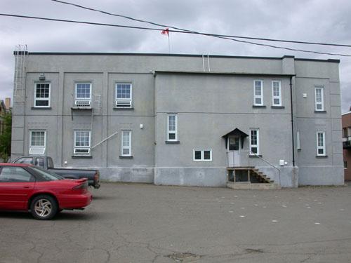 This image displays the exterior finish in stucco and the flat roof with a slight serrated cornice.; PNB 2004