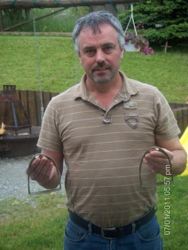 Dennis Smith holding silver saddle stirrups that were reportedly found at Peter's Finger, New Perlican, NL. Photo taken 2011. ; © Heritage New Perlican 2011