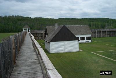View of building and stockade catwalk inside the fort; Parks Canada / Parcs Canada, 2003