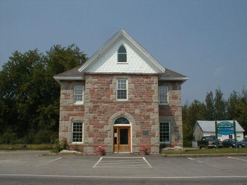 This front facade view of the building presents the approximately square main section of the building with a medium pitch hip roof.; PNB 2004