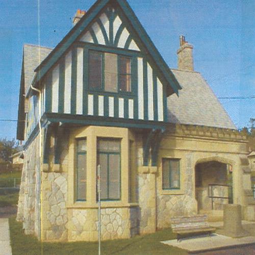 Exterior view of the Belmont Road Main Gatehouse, showing the building’s asymmetrical composition which features a square ground floor plan, surmounted by an overhanging L-shaped second floor and hipped roof, 2000.; Department of National Defence/Ministère de la Défense nationale, D. Cebula, 2000.