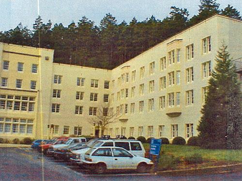 General view of the front facade of the Nixon Block RR24A showing elements influenced by the Tudor Revival Style such as the three-storey mullioned bay windows, the engaged buttresses, and the decorative shields, 2000.; Department of National Defence / Ministère de la Défense nationale, 2000.