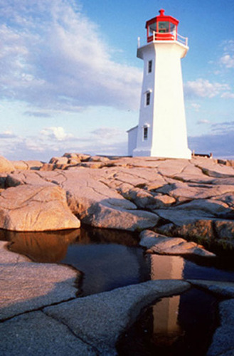 General view of the Lighthouse at Peggy’s Point, demonstrating its relationship with the site, which consists of a barren rock outcrop and natural vegetation without visible paths leading to the building or any other structures in the immediate vicinity, ; Department of Fisheries & Oceans Canada | Département de pêches et océans Canada, 1995