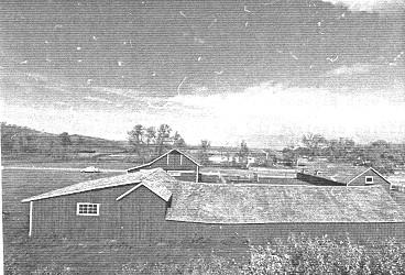 Side view of the Implement shed, showing its tall gable-roofed mid-section, 1992.; (Public Works Canada, Architectural & Engineering Services - Canadian Parks Service, Western Regional Offices, / Travaux publics Canada, services d'architecture et de génie - Service canadien des parcs, Bureau de la région de l'Ouest, 1992).
