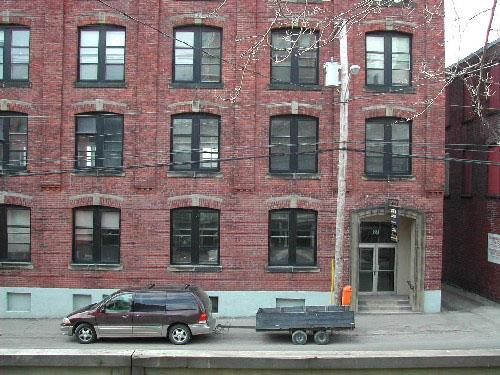 This photograph displays the style of the windows, the north entrance, and the projecting course of bricks that runs vertically through the top four floors, 2004.; City of Saint John