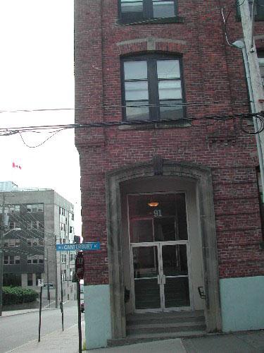This photograph shows the recessed entranceway, large transom window, and the segmented sandstone arch with keystone, 2004.; City of Saint John