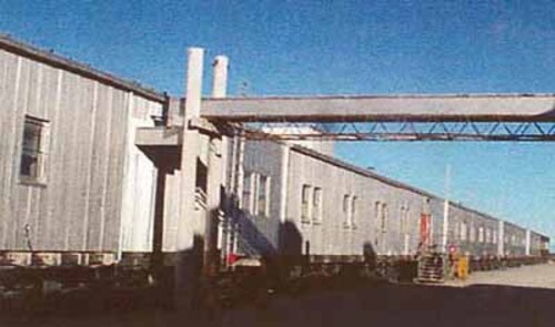 General view of Module Train B, showing its exterior metal cladding and the size, form and spacing of door and window openings dictated by each modules function, 1998.; Canada, North Warning System Office / Bureau du système d'alerte du Nord, 1998.