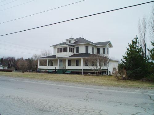 Lynch-Chouinard House, also known as the White House, showing hipped roof with its hipped dormer and veranda on three sides.  ; Village of Saint-Quentin