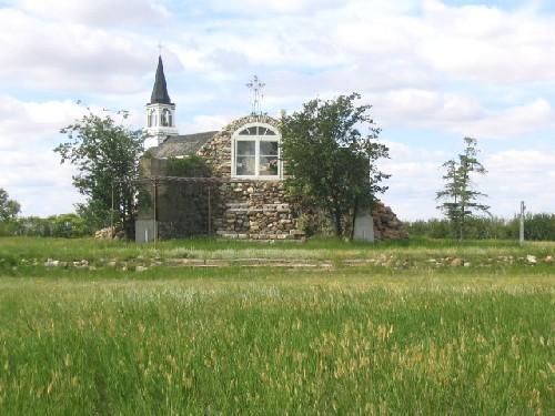 View northwest at fieldstone shrine (note iron cross on top of the grotto, replica; Government of Saskatchewan, Marvin Thomas, 2004.