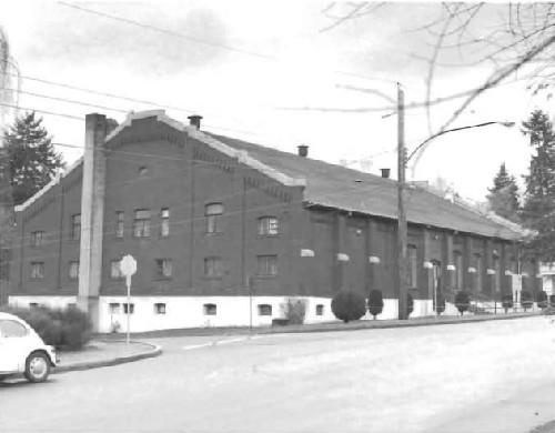 View of the Armoury, showing the large scale, symmetrical, low-massed building with a gable-roof, 1988.; Ministère de la Défense nationale / Department of National Defense, 1988.