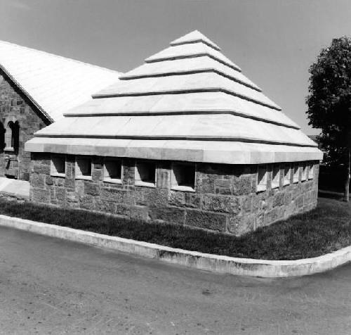 Corner view of Building 7, showing its roof construction of a concrete shell faced with smooth stones laid so as to create horizontal bands, 1980.; National Defense Ministry of Canada / Ministère de la Défense Nationale (1980).