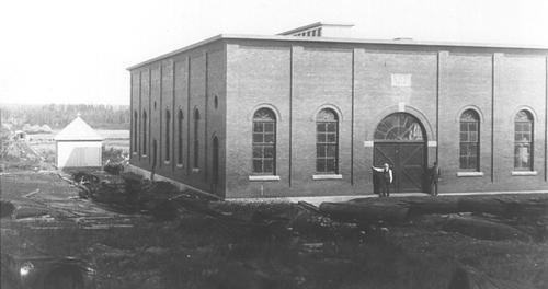This photo, taken after the completion of the Highfield Street Pumping Station, shows the arched openings and square massing associated with the Italianate style.; Moncton Museum