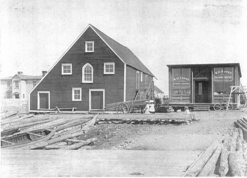 The Mockbeggar Plantation c1920s.  The large building in the center of the photo is referred to as the "fish store".  To the right of that is the barter shop and to the left is the Bradley residence.  ; Department of Tourism, Culture and Recreation 2005
