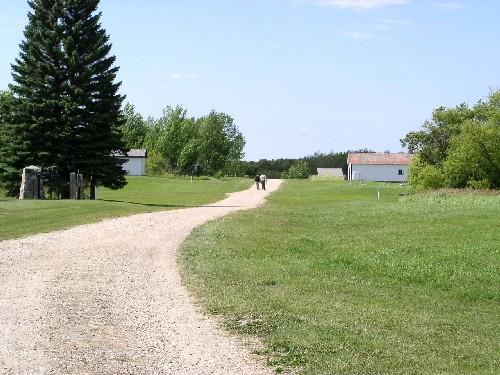 View west along location of village's mainstreet; replica blacksmith's shop on right; cellar depressions in right foreground, 2004.; Government of Saskatchewan, Marvin Thomas, 2004.