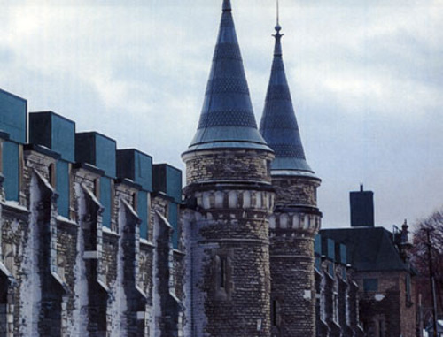 View of buttresses creating a regular definition of bays, faux gun embrasures on the ground level and elaborate French Renaissance-style windows breaking the eave line at the second storey.; Parks Canada | Parcs Canada